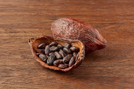有机产品摄影照片_可可树的有机天然豆荚充满棕色可可豆放置在木背景。可可豆半豆荚