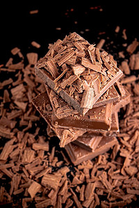 碎块摄影照片_碎块和磨碎的黑巧克力。在黑色的背景上..碎块和磨碎的黑巧克力。