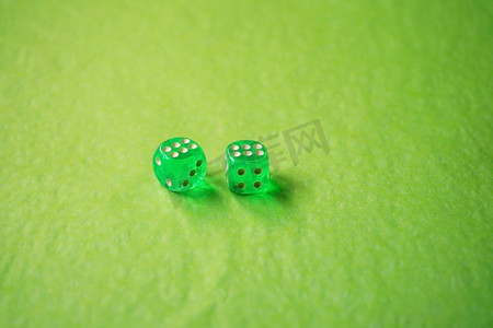 一个充满活力的单色宏观与领域深度约两个绿色玻璃赌博骰子与两个幸运数字六在绿色背景。