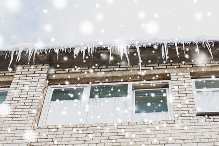 起居室摄影照片_季节、住房和冬季概念-建筑或居住房屋立面上的冰柱。建筑物或起居室正面的冰柱