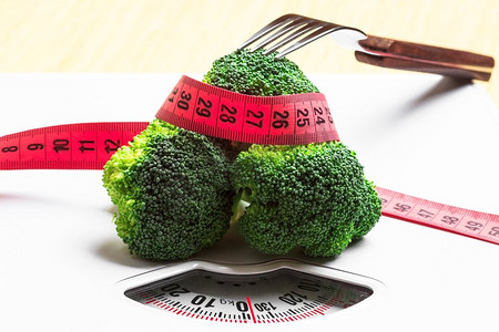 饮食健康饮食体重控制概念。特写绿色花椰菜卷尺和叉子在白色鳞片