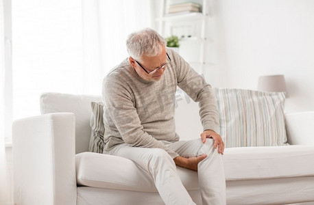 人，保健和问题概念—不快乐的老年人遭受膝盖疼痛在家。老人家中膝盖酸痛