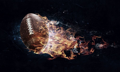 橄榄球在火火焰在黑暗背景。混合媒体。美式足球游戏概念混合媒体