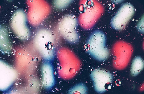 一个美丽和充满活力的宏观油泡在水与白色和粉红色心脏图案模糊在黑色背景