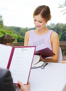 看菜单摄影照片_约会，奢侈品和人的概念—愉快的妇女阅读菜单在餐馆在夏天背景一对夫妇在餐厅的菜单