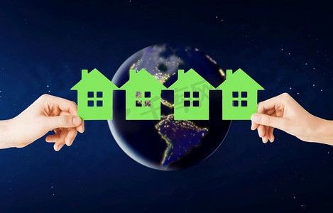 生态，环境和家园概念—手拿着绿色的房子在地球上的行星在太空。在太空中，手握着地球上的温室
