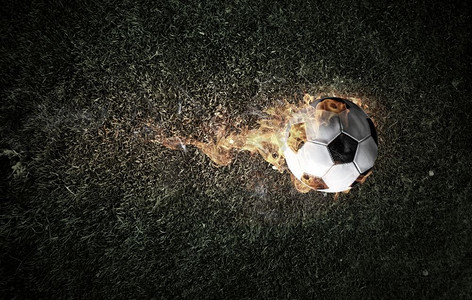 足球比赛的概念与球在火焰。混合媒体。足球着火了