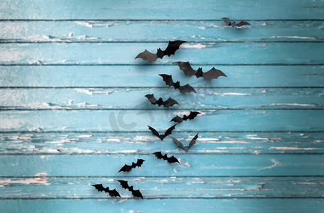 万圣节，装饰和可怕的概念—黑色蝙蝠飞行在蓝色破旧的板背景黑色蝙蝠在蓝色破旧的董事会背景