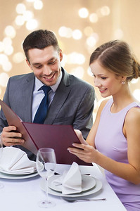 约会，奢侈品和人概念—有菜单的愉快夫妇在餐馆在节日灯在米色背景一对夫妇与菜单在餐厅