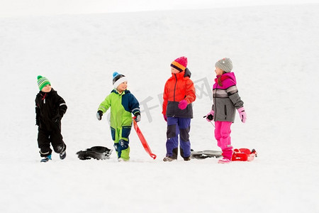 冬天小朋友摄影照片_童年、雪橇和季节概念-一群快乐的小朋友在冬天拉雪橇。冬天玩雪橇的快乐小朋友