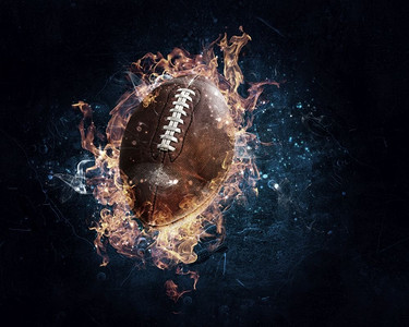 火焰足球摄影照片_橄榄球在火火焰在黑暗背景。混合媒体。美式足球游戏概念混合媒体
