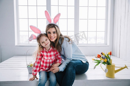 女孩妈妈兔耳朵坐在装有复活节彩蛋的篮子旁边