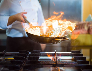厨师烹饪和做在餐厅厨房的食物火炬。厨师在食物上做火焰