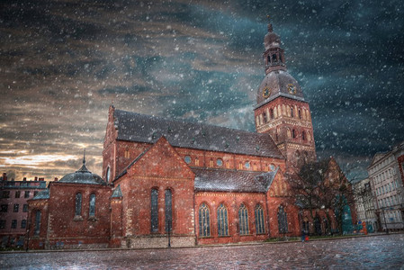 冬天街道摄影照片_冬天会下雪。圣彼得的里加教堂和古城的街道。圣彼得里加教堂