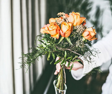 女性在家中用玻璃花瓶手工制作玫瑰花束插花