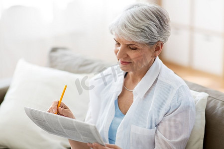 年龄和人的概念—老年妇女在家中标记报纸广告。老年妇女在家中标记报纸广告