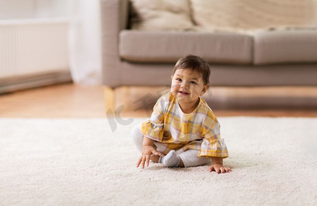 童年和人的概念--快乐微笑的女婴坐在地板上回家。开心的笑着的女婴坐在地板上回家