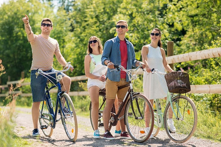 人、休闲、生活理念—快乐的年轻朋友们在夏天骑固定齿轮自行车。快乐的朋友骑固定齿轮自行车在夏天