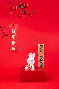 2023新年摄影照片_2023兔年新年兔子摆件台历红色背景摆放