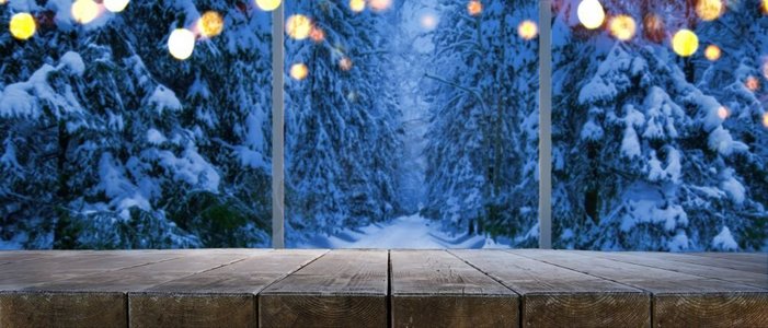 空的桌子在家里与全景通过窗口雪树在冬天森林背景夜冬森林透过窗户