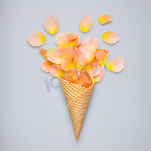 富有创意的静物冰激凌华夫饼蛋卷，灰色背景上有玫瑰花瓣。