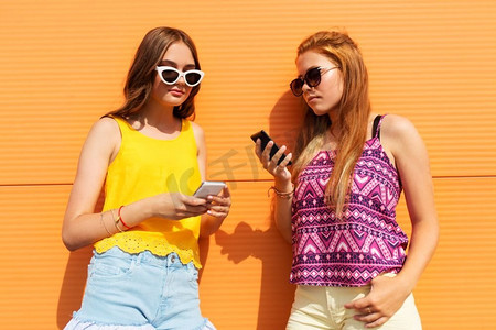 科技、休闲和人的概念--十几岁的女孩在户外穿着夏装，拿着智能手机。夏季户外活动中十几岁的女孩拿着智能手机