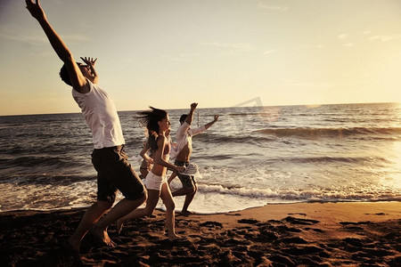 灯塔大海摄影照片_快乐的年轻人在夕阳时分在灯塔上欢快地奔跑和跳跃