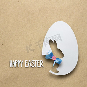 有创意的复活节概念照片，一只兔子在棕色背景下用纸做的鸡蛋里。
