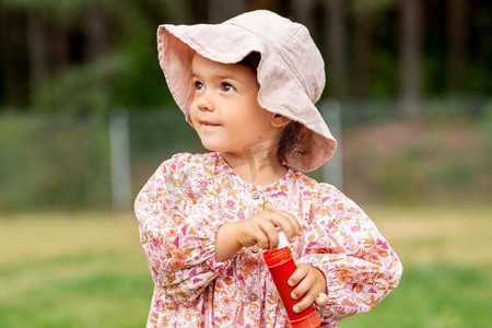 童年，休闲和人的概念—快乐的小女婴与肥皂泡吹风机在夏天。快乐的女婴与肥皂泡吹风机在夏天