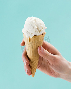 手拿香草冰淇淋甜筒蓝色背景