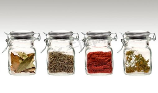 一系列的四个透明玻璃罐不同的香料和草药。