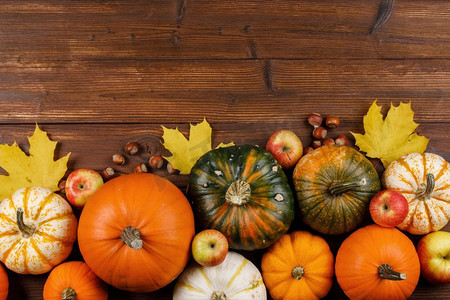 秋收时，木质背景上挂着南瓜、苹果、榛子和枫叶，静悄悄的。木桌上的秋收