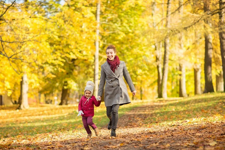家庭，季节和人的概念—快乐的母亲和小女儿在秋天公园散步。快乐的母亲和小女儿在秋天公园