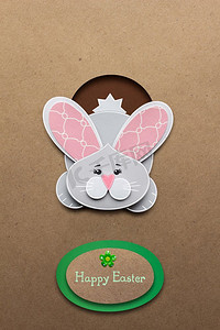 有创意的复活节概念照片，一只兔子在棕色背景下用纸做的洞里。