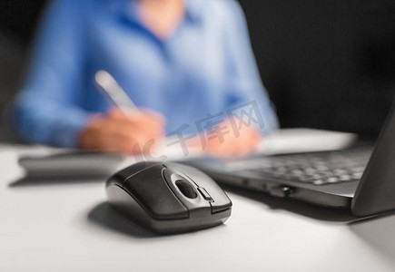 商业、教育、人和科技概念-夜间办公室桌上的电脑鼠标特写。夜间办公室桌子上的电脑鼠标