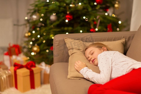 圣诞节、假日和童年概念—女孩睡在家里的沙发上。女孩睡在沙发上在圣诞节