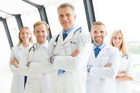 一支成功的医生团队。一组成功的医生双臂交叉站在医院里，面带微笑地看着摄像机