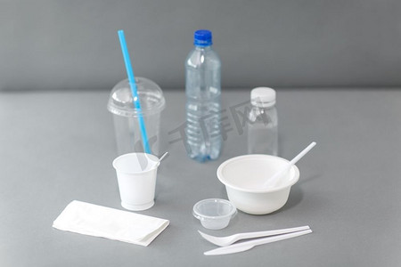 器皿摄影照片_餐饮、回收、生态理念--一次性塑料餐具，灰色底色。餐桌上有一次性塑料餐具