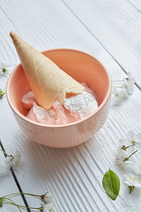 香草冰淇淋和华夫饼甜筒在一个粉红色盘子在白色木背景香草冰淇淋在一个盘子