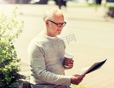 大众媒体、新闻和人物概念—在城市里读报纸喝咖啡的老年人。一位老人在看报纸喝咖啡