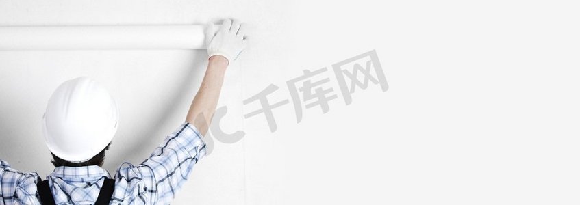 工人附加白色壁纸到空墙复制空间的背景文本。工人贴壁纸