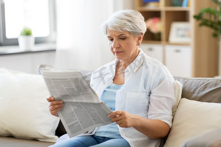年龄和人的观念—老年妇女在家读报。在家里读报纸的老年妇女