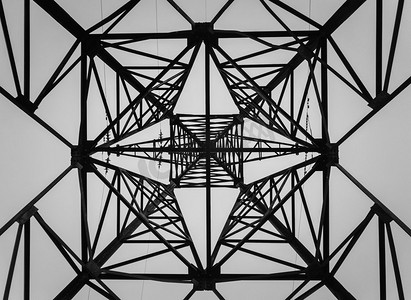 在一个桁架立柱结构的下面。不同的几何形状，钢结构的图案。电线杆的金属质地。