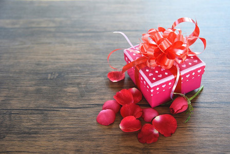 礼品盒粉红色与玫瑰花瓣花浪漫的礼物情人节在木质朴纹理背景顶视图  