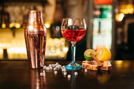 摇骰子摄影照片_玻璃饮料，摇壶，酸橙，柠檬，盐和骰子在木制酒吧柜台