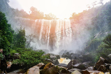 瀑布风景摄影照片_瀑布大而高的溪流山与悬崖石头洞穴在丛林热带雨林绿色美丽的风景泰国