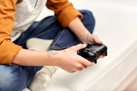 休闲，技术和人的概念—男孩与游戏手柄玩视频游戏在家里。男孩与游戏手柄玩视频游戏在家里