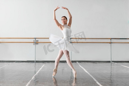 美丽的芭蕾舞演员排练在芭蕾舞课，barre和白色墙背景。美丽的芭蕾舞演员排练在芭蕾课
