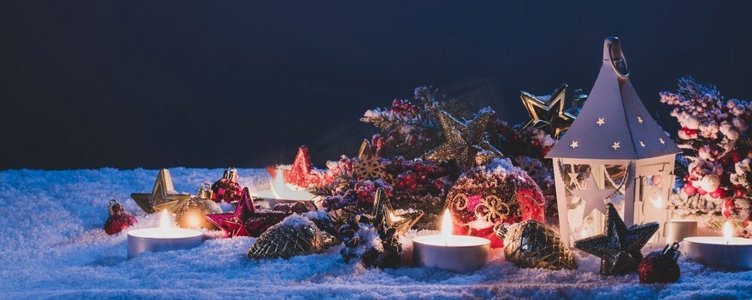 树枝晚上摄影照片_发光的圣诞灯笼和装饰冷杉树枝和小玩意儿在雪。圣诞灯笼和装饰在雪