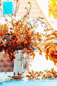 秋天的鲜花束在蓝色的桌子上在窗口与阳光。舒适的家居室内装饰。秋季静物，前视图